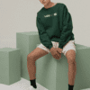 Model wearing green Leversi sweatshirt with front logo in studio streetwear shoot