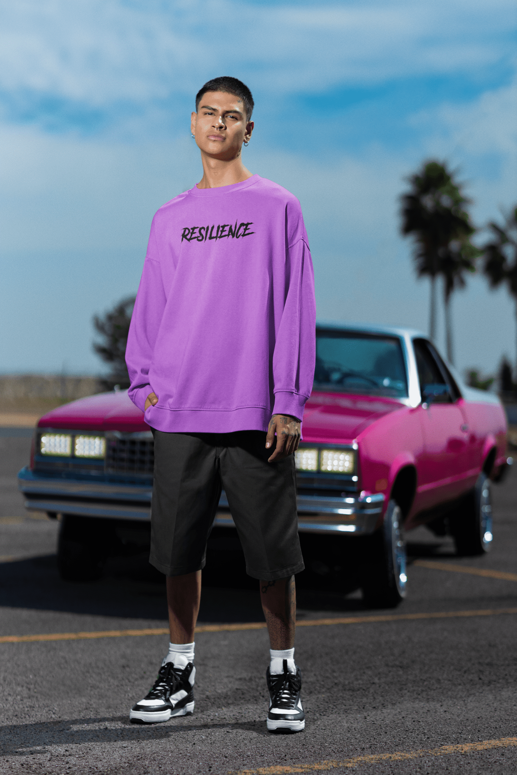 Model wearing a purple oversized resilience sweatshirt styled outdoors with a vintage car.