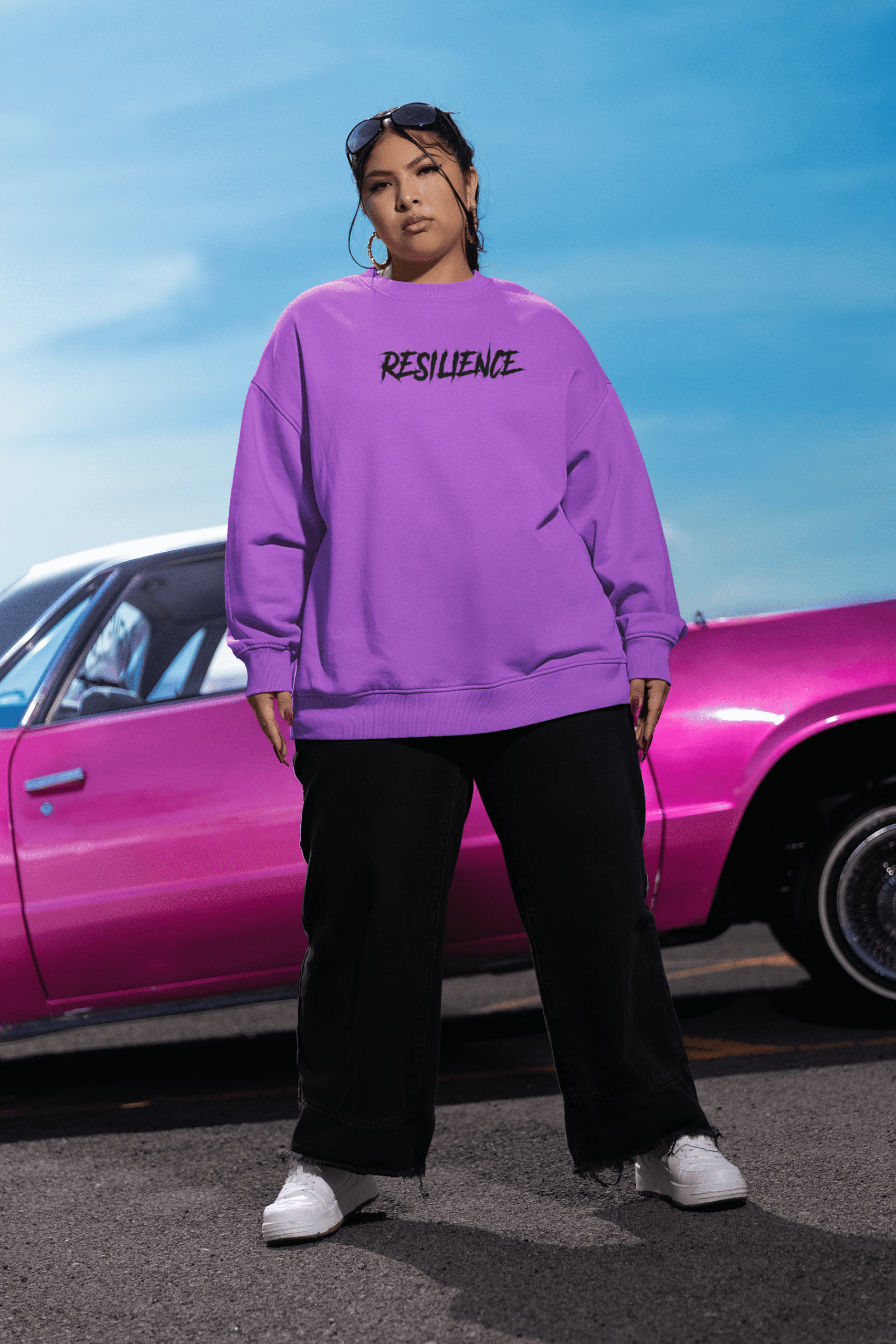 Model wearing a purple oversized resilience sweatshirt styled outdoors with a vintage car.