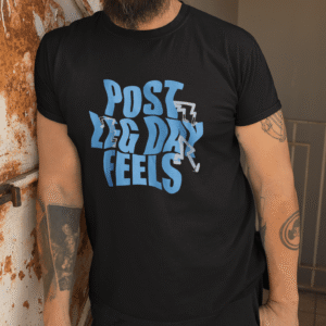 Man wearing black Post Leg Day Feels gym t-shirt standing against rustic metal wall