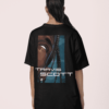 Back view of a person wearing a black graphic T-shirt featuring an illustrated face design and the text “Travis Scott.”