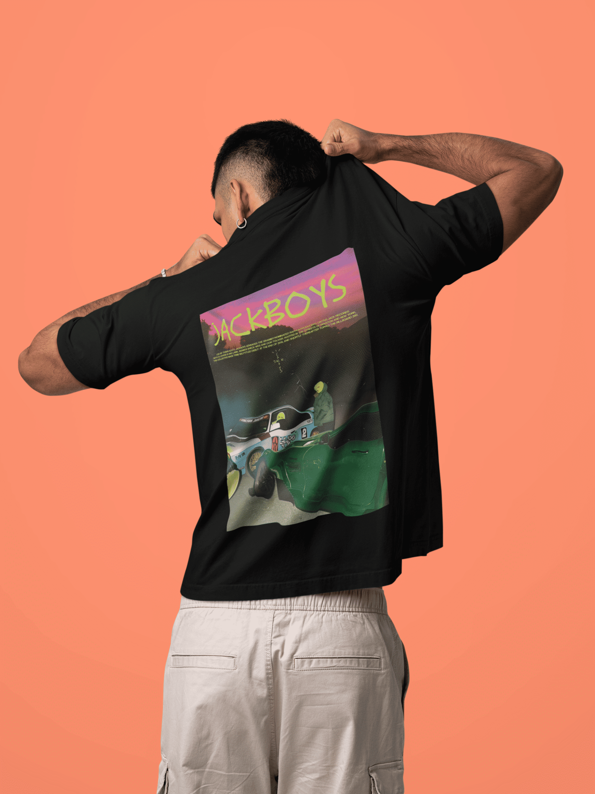 Man lifting his black T-shirt to show a large JACKBOYS graphic on the back featuring neon text and a stylized car scene.