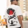 Man wearing a white oversized T-shirt with a black dragon and red sun graphic on the back, standing outdoors in an urban setting.