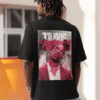 Man wearing a black T-shirt with a large red Travis Scott graphic on the back, standing outdoors in casual streetwear.