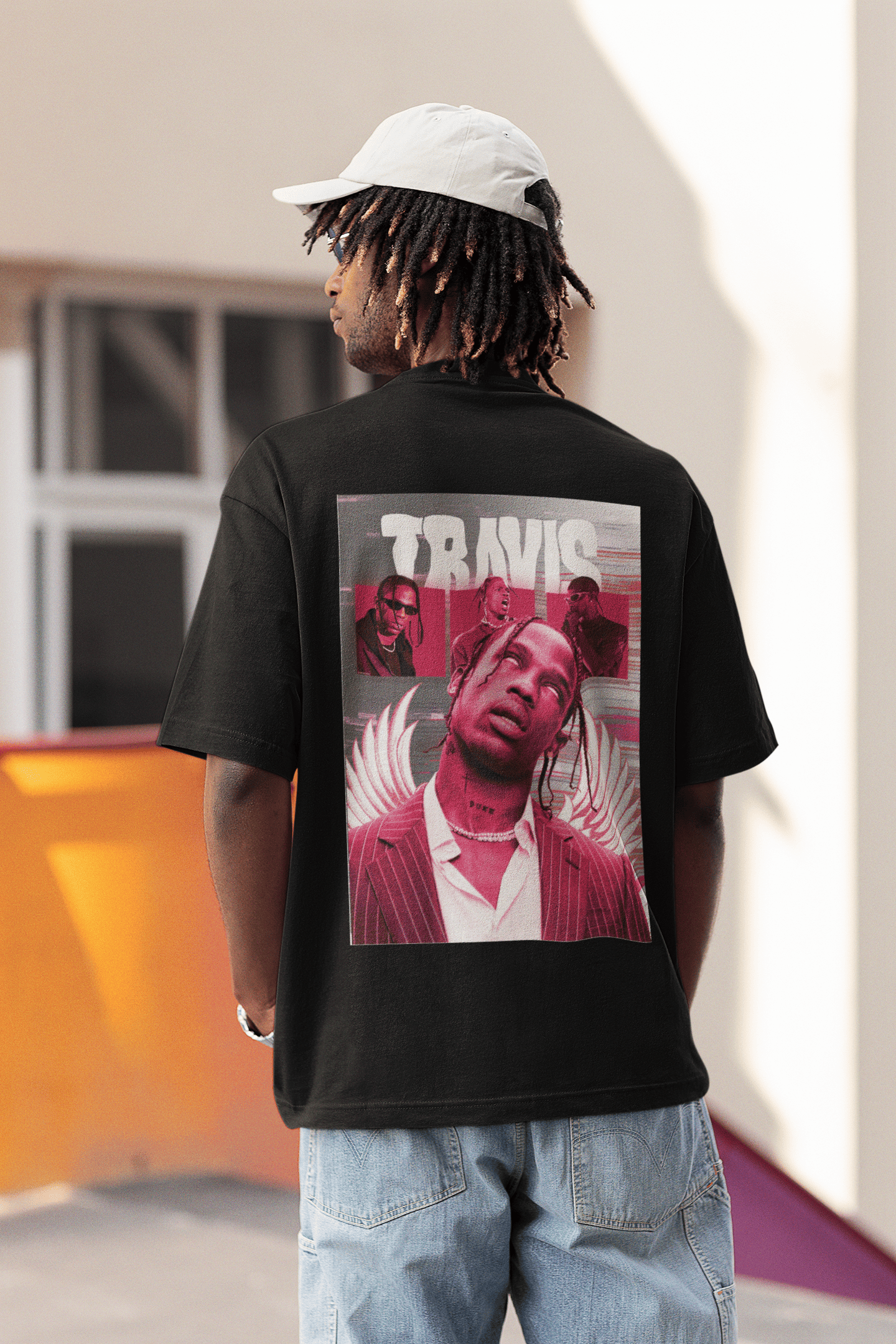 Man wearing a black T-shirt with a large red Travis Scott graphic on the back, standing outdoors in casual streetwear.