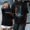 Two people wearing Travis Scott–themed black graphic T-shirts, one showing the back print and one wearing the front logo design, standing outdoors.