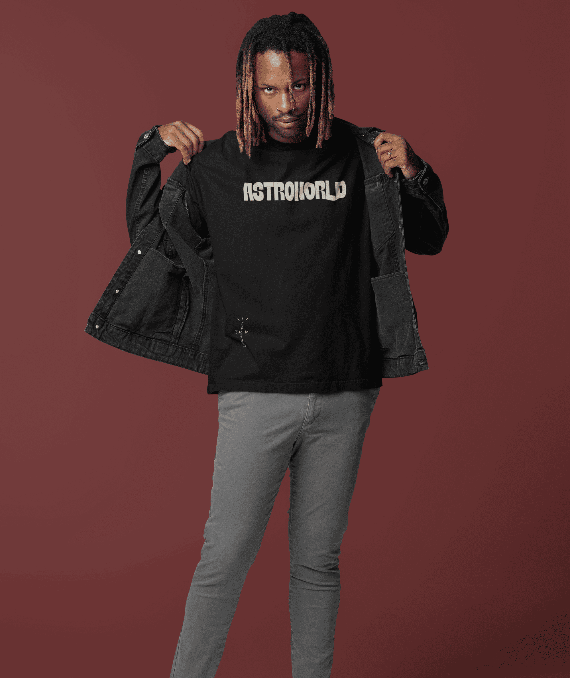 Man wearing a black Astroworld T-shirt and denim jacket posing in studio.