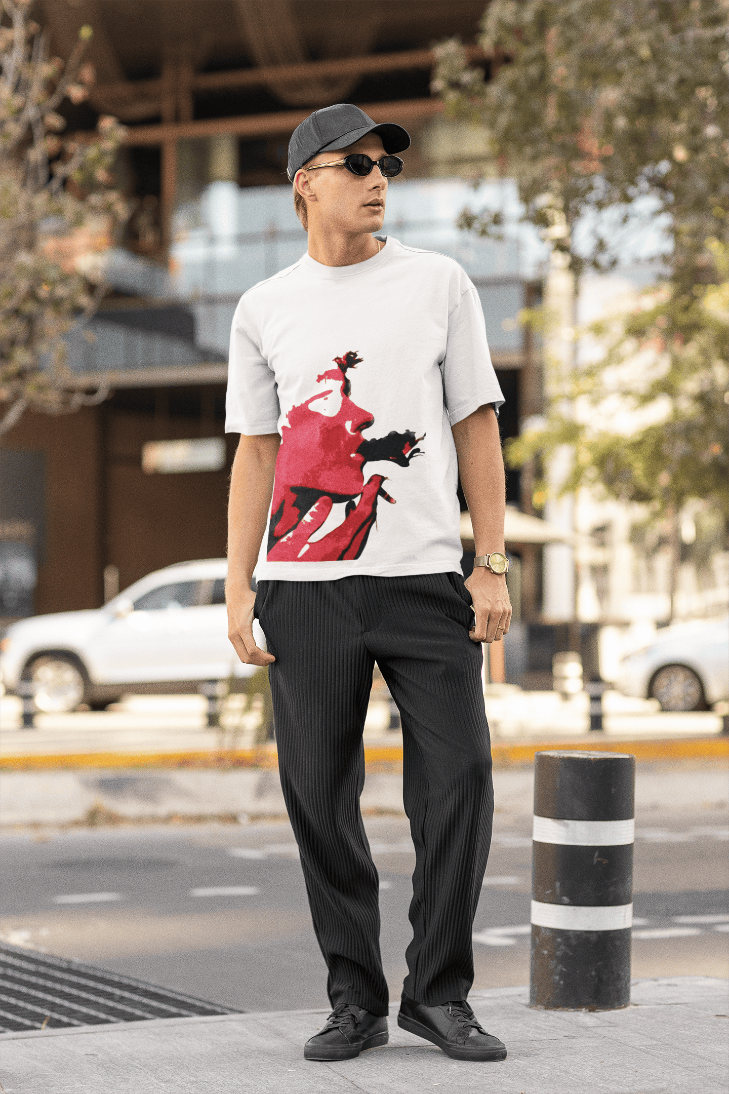 Man wearing white oversized T-shirt with bold red abstract face print while standing outdoors in a street-style setting.