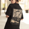 Person wearing a black T-shirt with a large Travis Scott “UTOPIA” back print featuring a dramatic sepia-toned image of a figure standing in rising smoke.