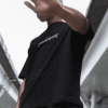 Person wearing a black Travis Scott–themed graphic T-shirt outdoors with their hand raised toward the camera.