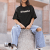 Woman wearing a black Astroworld T-shirt and ripped jeans, sitting outdoors on a concrete block.