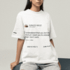 Woman wearing a white Kanye West tweet graphic T-shirt while sitting on geometric blocks in a studio.